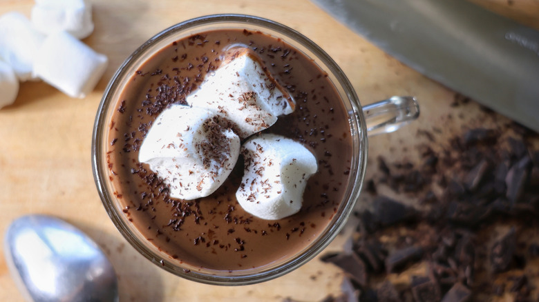 mug of hot chocolate with marshmallows and grated chocolate on cutting board