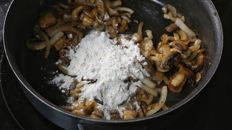 flour atop skillet of onion and mushrooms
