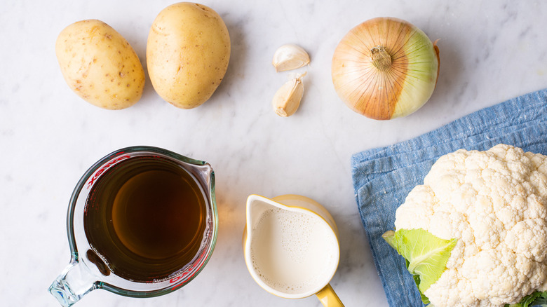 Ingredients gathered on a marble counter to make cauliflower soup.