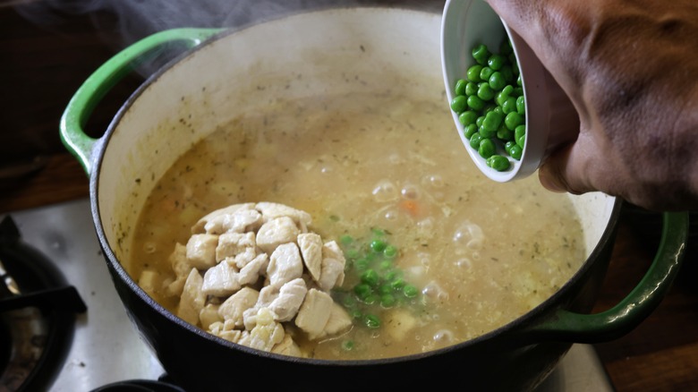 adding peas to pot of soup