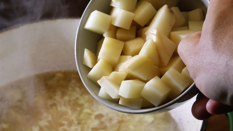 bowl of cubed potatoes going into soup pot