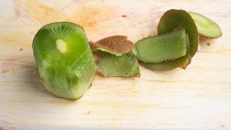 Close up of a sliced up kiwi fruit on a wooden cutting board