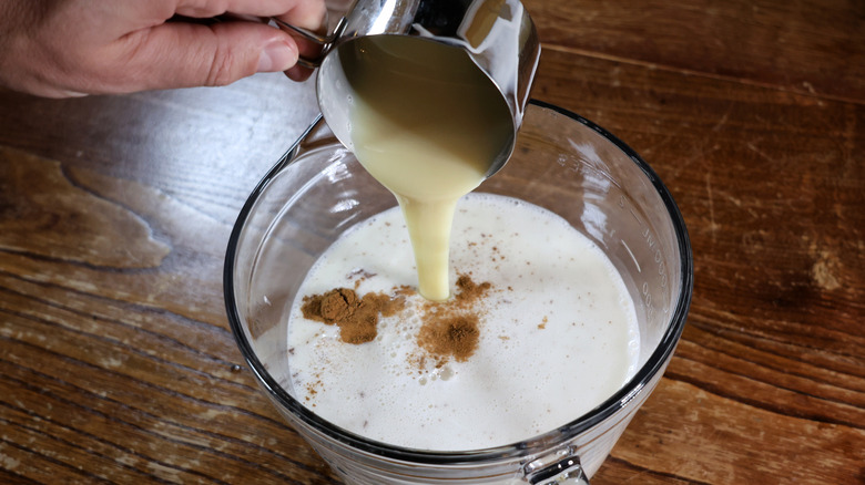 pouring condensed milk into bowl of horchata