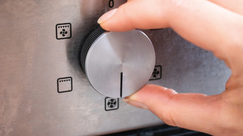 Hand turning dial on oven