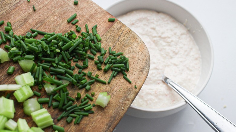 adding chives and celery to shrimp dip