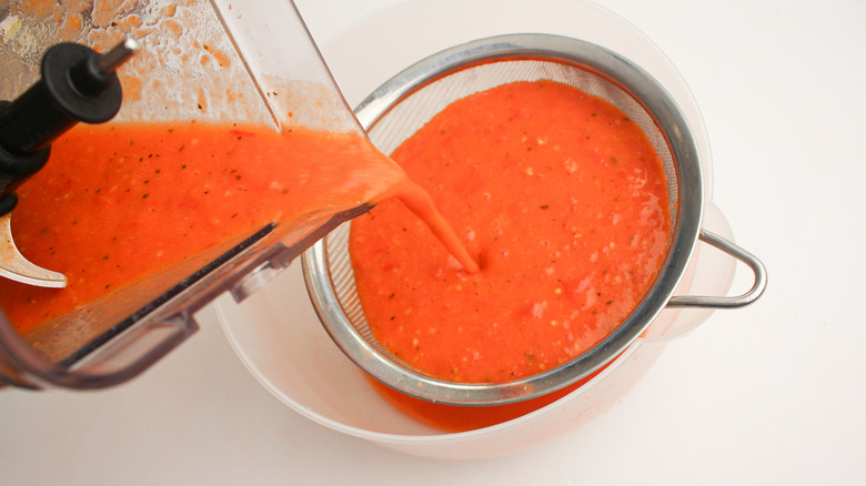 Tomato soup pouring through a sieve