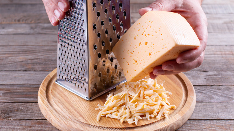 hands grating cheese block