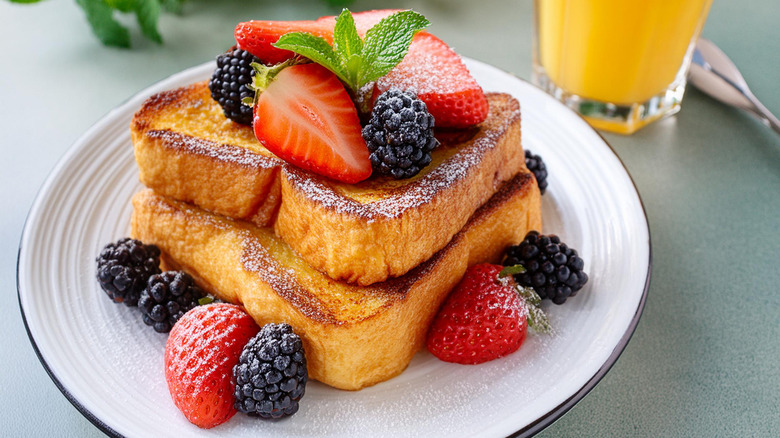 two slices of French toast with strawberries and blackberries