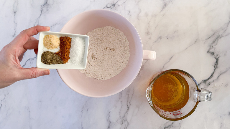 hand adding seasoning to flour