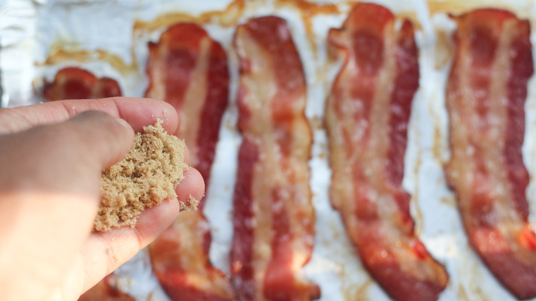 hand sprinkling brown sugar on bacon