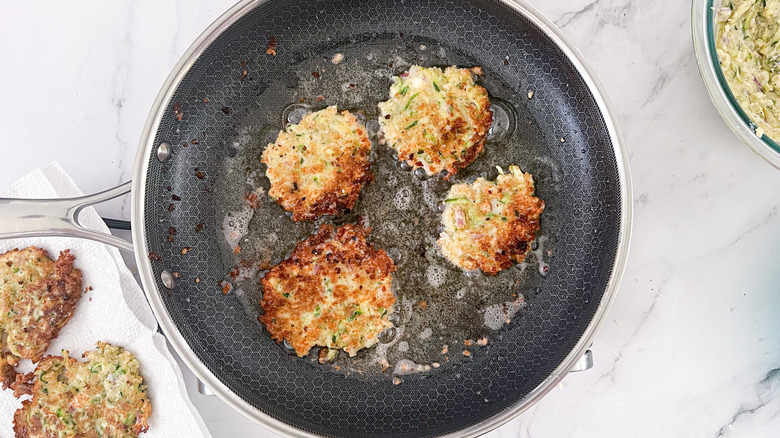 Zucchini fritters frying in a pan