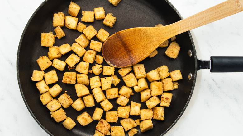 Tofu cubes frying in pan