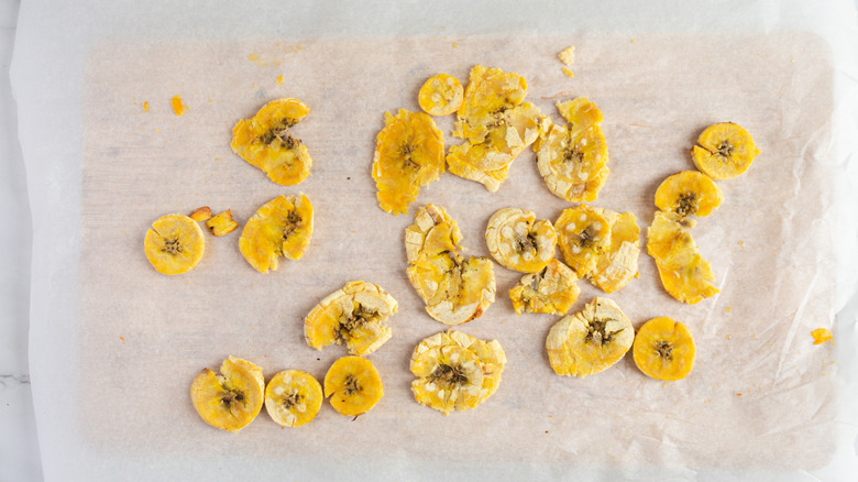 squished tostones on parchment paper