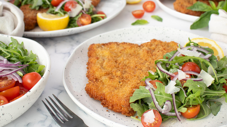 breaded cutlets and salad on white plates