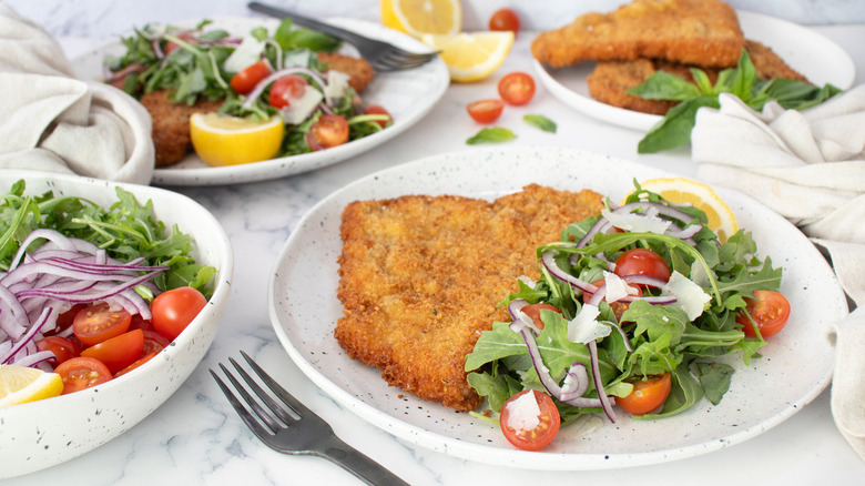 breaded cutlets and salad on white plates