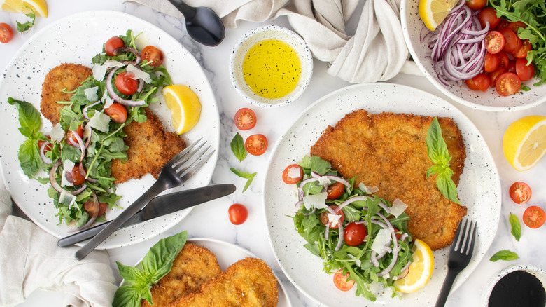 breaded cutlets and salad on white plates