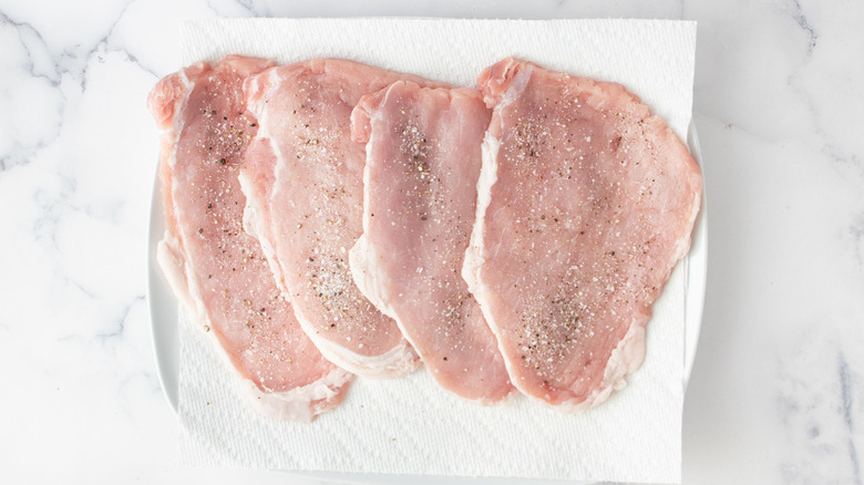 seasoned raw veal cutlets on a paper towel