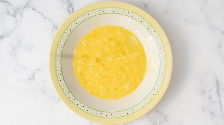 raw eggs in a round, yellow-rimmed bowl