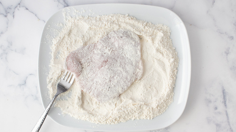 raw veal cutlet covered in flour