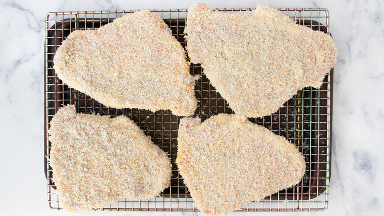 breaded uncooked cutlets on a wire rack