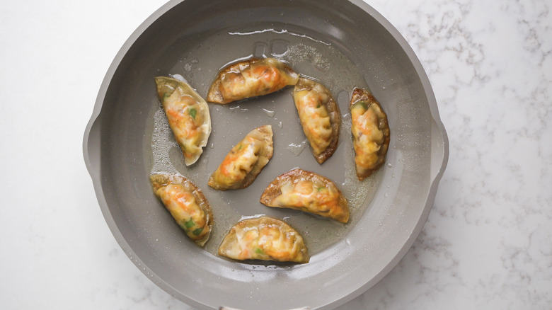 steaming potstickers in pan