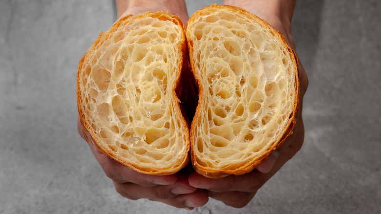 person holding croissant cut in half