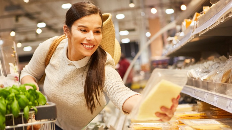 woman looking a cheese in supermarket case