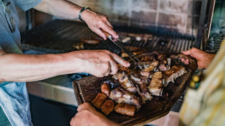 man cutting steak near grill 