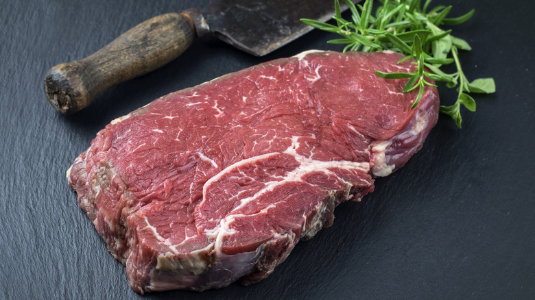 Bottom round steak rests beside knife