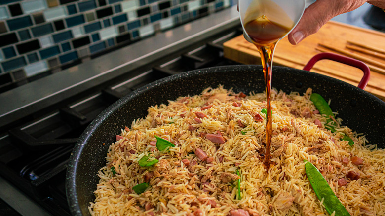 pouring sesame oil into fried rice