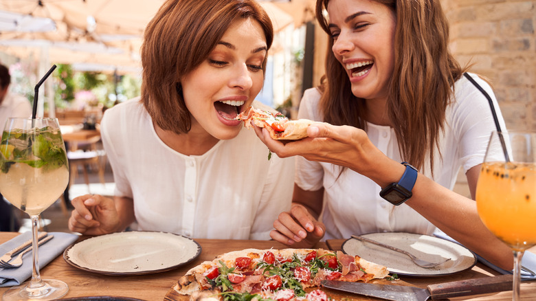 People feeding each other pizza