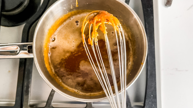 Caramel cooking in pan with whisk above