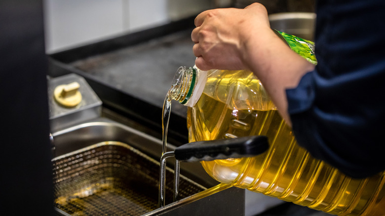 Chef pouring oil into fryer