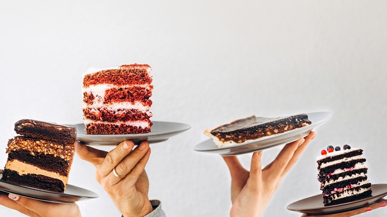 hands holding up slices of cake