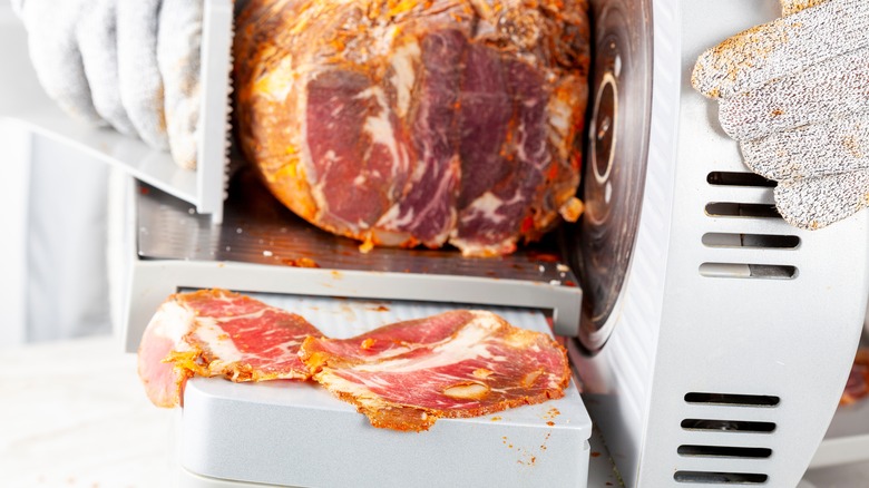 deli worker slices meat