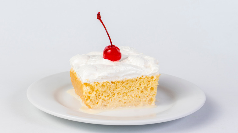 slice of tres leches with maraschino cherry