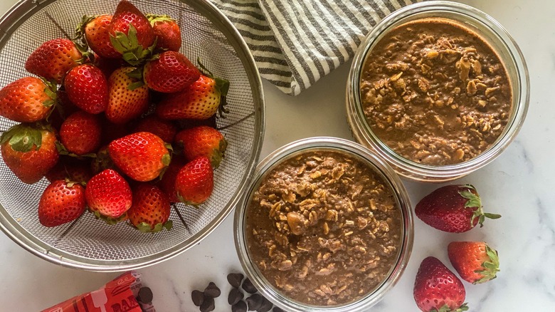 oatmeal in two containers by bowl of strawberries