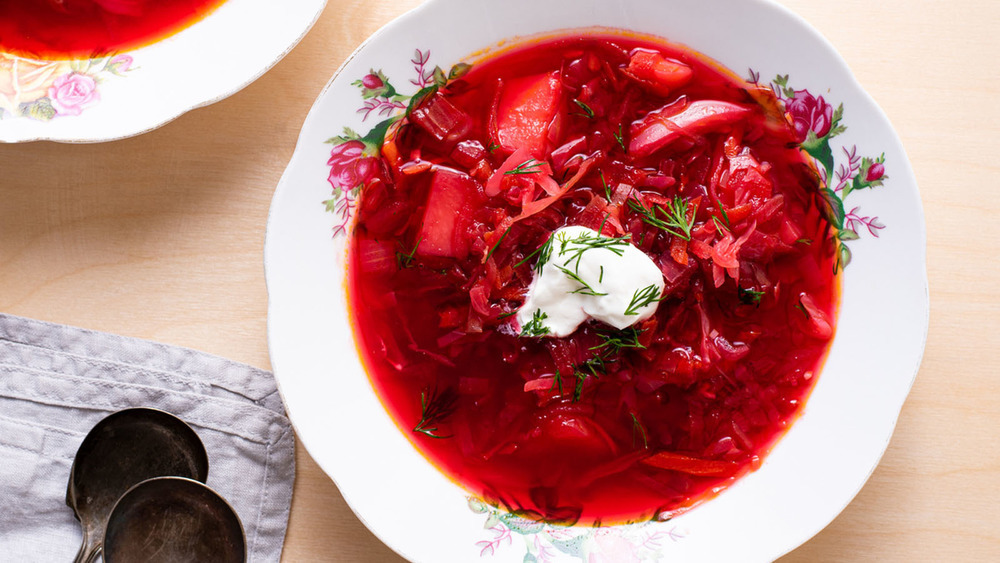 Borscht in white bowl with sour cream and dill