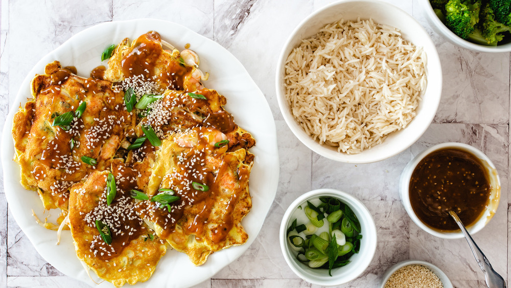 Egg Foo Young on white plate with rice, sauce, and green onions