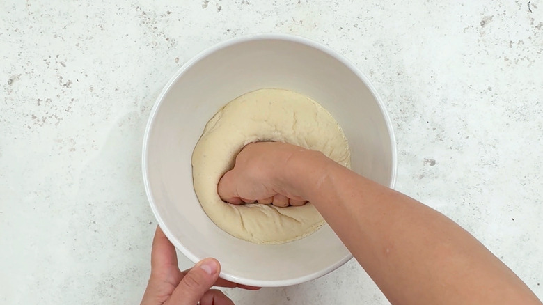 deflating dough with fist