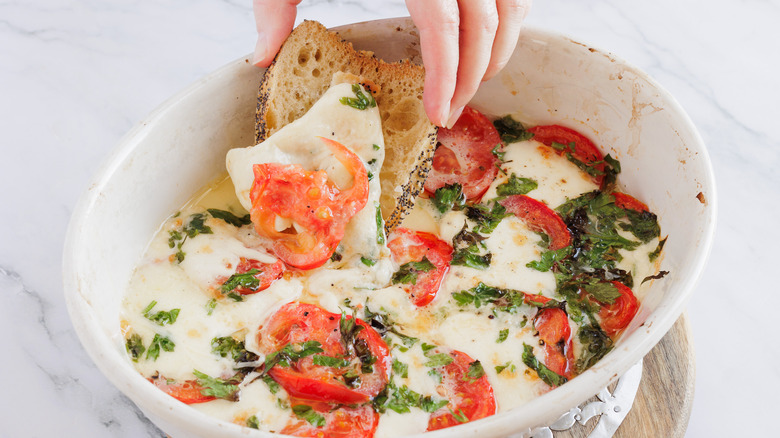 dipping baguette into baked mozzarella