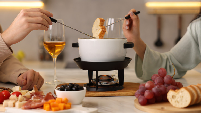 Dipping bread into fondue pot