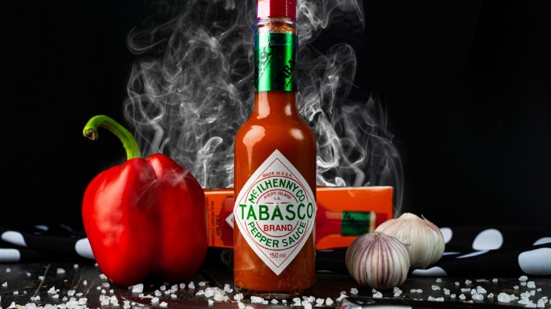 Bottle of Tabasco sauce with garlic and peppers in background