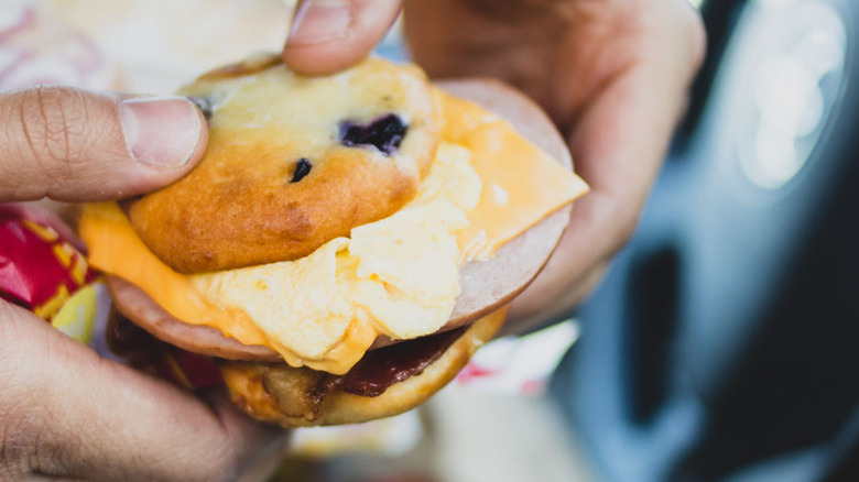 Person holding Carl's Jr. Blueberry Muffin sandwich