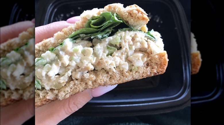 Hand holding chicken salad sandwich