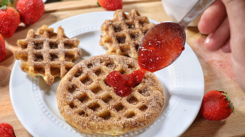 spoon spreading strawberry sauce on churro waffle Mickey Mouse face