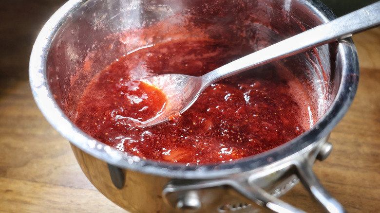 saucepan full of strawberry sauce with spoon in it