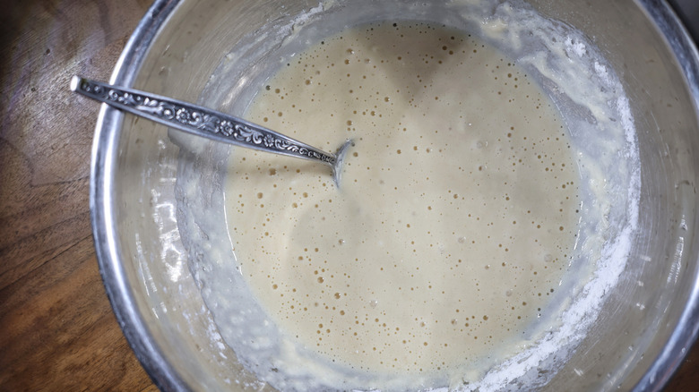 metal mixing bowl full of waffle batter with spoon in it