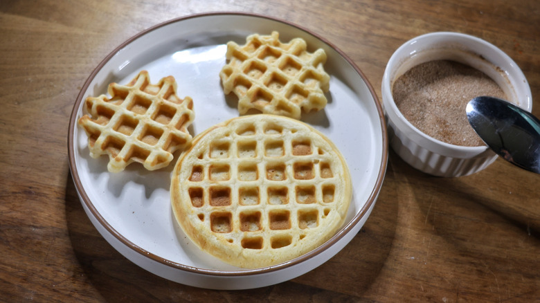 mini waffle Mickey Mouse face on a plate with a ramekin of cinnamon sugar next to it