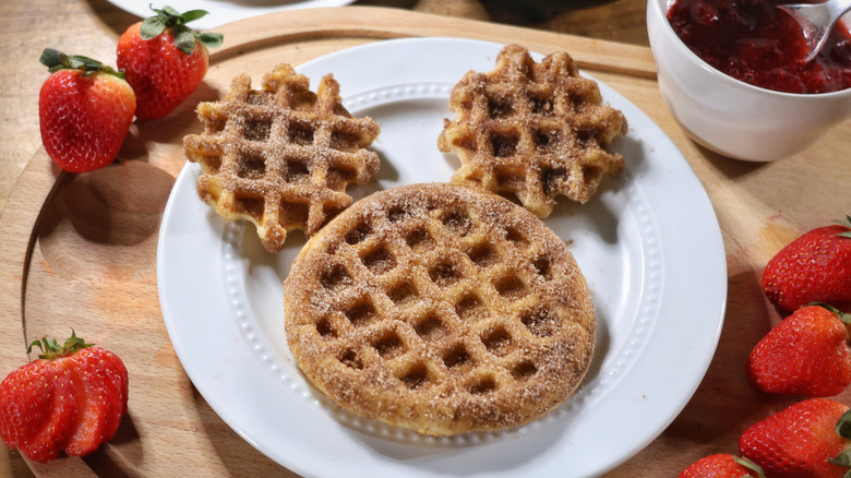 mini churro waffle Mickey Mouse on plate sith strawberries and bowl of strawberry sauce